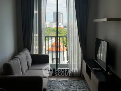 Modern living room with balcony and city view, featuring cozy sofa and entertainment unit.