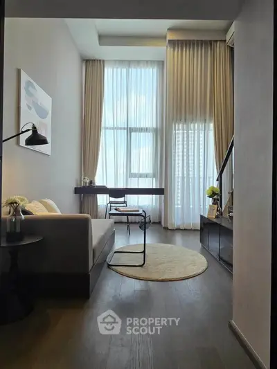 Modern living room with high ceilings and large windows, featuring elegant decor and natural light.