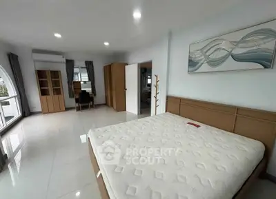 Spacious bedroom with modern furnishings and large windows for natural light.