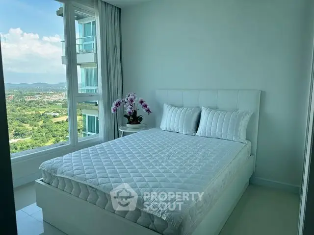 Bright bedroom with large window offering stunning city and nature views, featuring a cozy bed and elegant decor.
