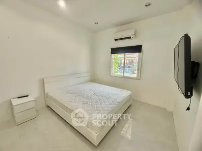 Spacious minimalist bedroom with white decor and large window view