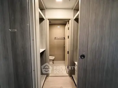 Modern bathroom with sleek wooden cabinetry and neutral tile flooring.