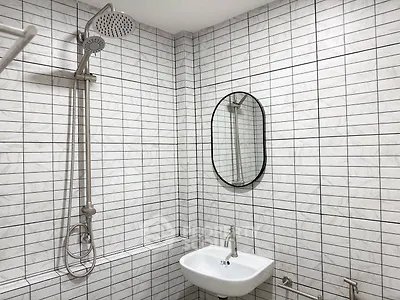 Modern bathroom with sleek shower and stylish oval mirror, featuring contemporary white tile design.