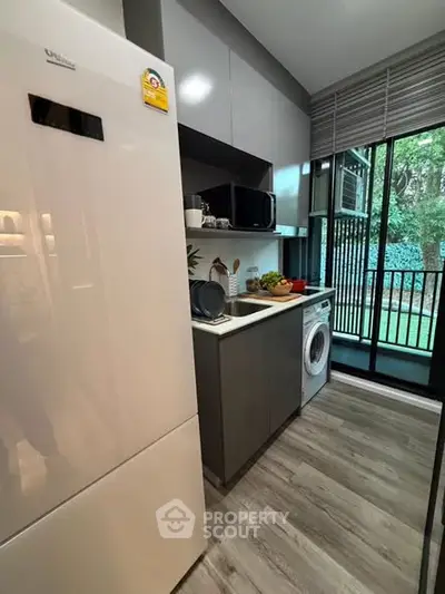 Modern kitchen with sleek appliances and a view of lush greenery through large windows.
