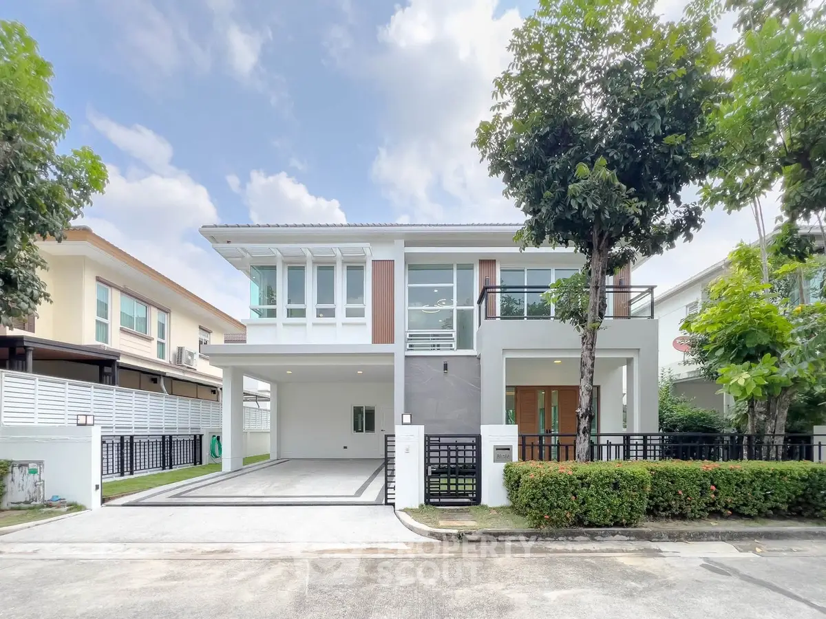 Modern two-story house with large windows and driveway in a serene neighborhood.