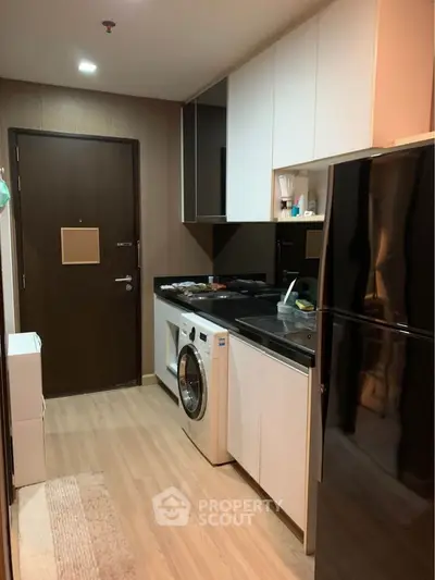Compact modern kitchen with sleek black appliances, including a washing machine, and ample cabinet space, perfect for urban living.