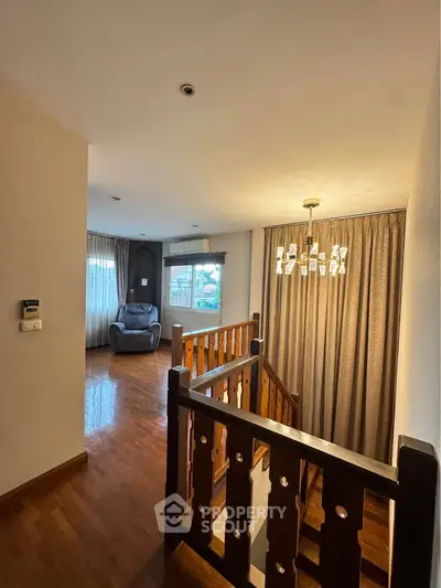 Spacious living area with wooden flooring and elegant lighting, perfect for relaxation.
