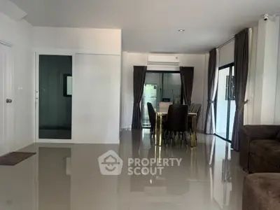 Spacious modern living and dining area with sleek tile flooring and large windows.