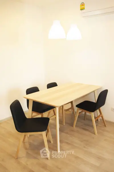 Modern dining area with wooden table and black chairs under stylish pendant lights.