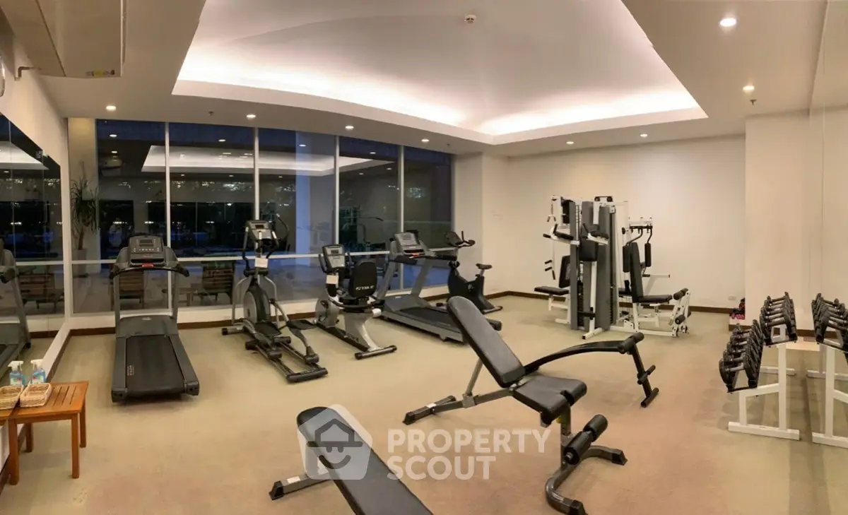 Spacious modern gym with state-of-the-art equipment and large windows for natural light.