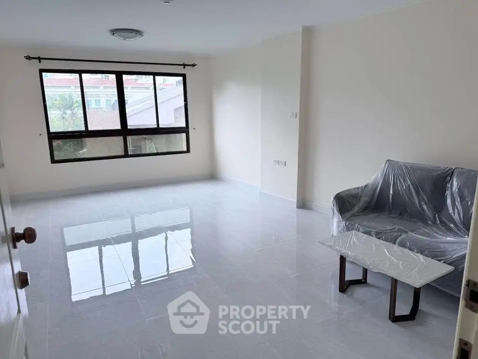 Spacious unfurnished living room with large window and tiled floor in modern apartment.