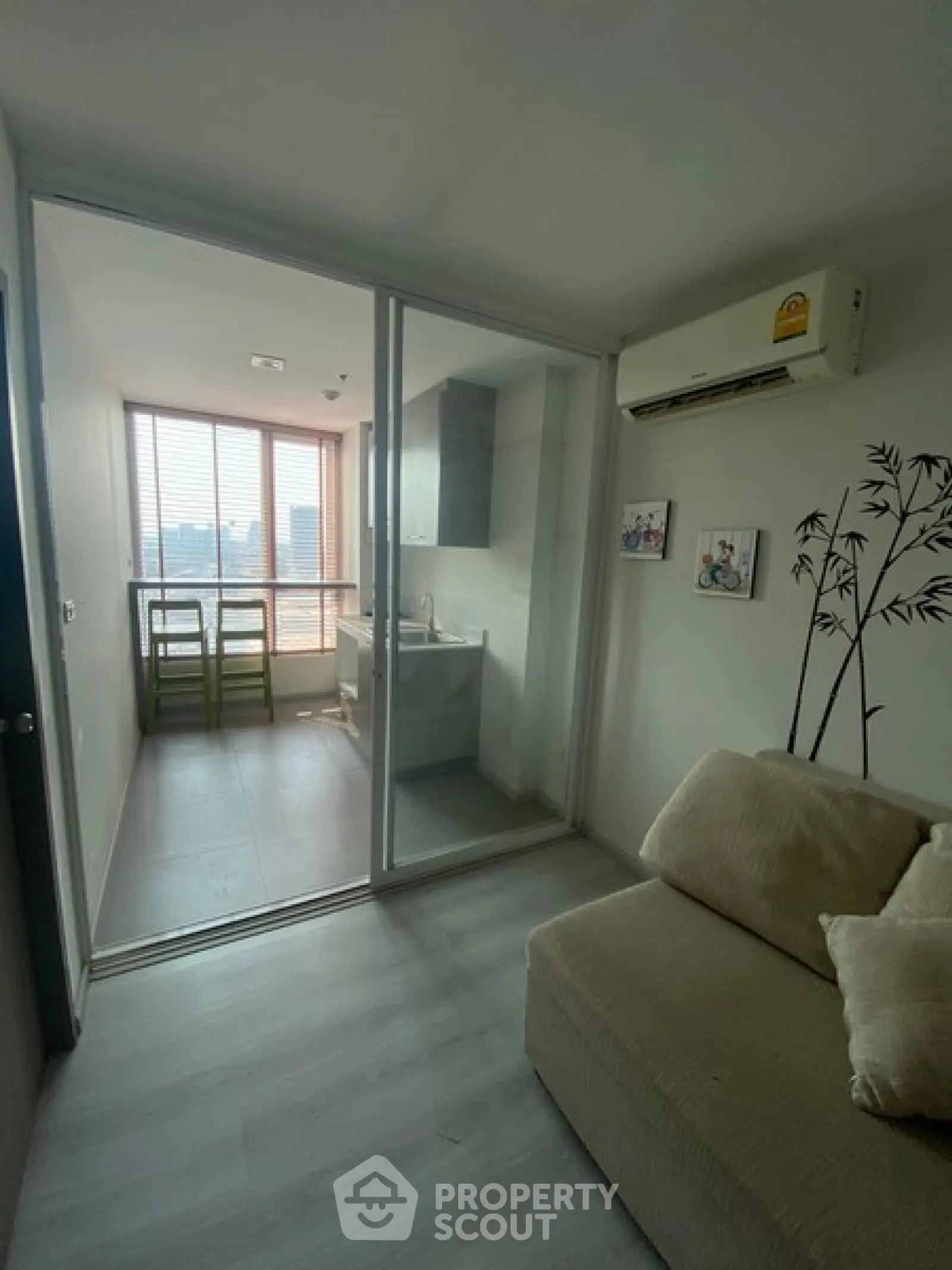 Cozy living room with sliding glass doors leading to a compact kitchen, featuring modern decor and city views.