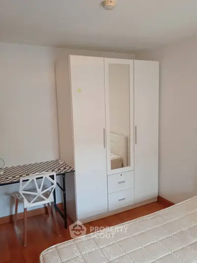 Cozy bedroom with modern wardrobe and stylish chair, perfect for comfortable living.