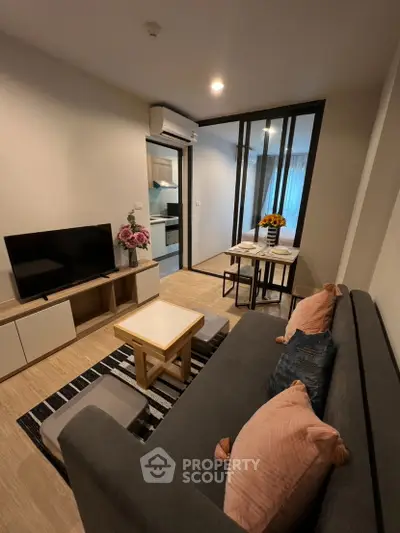 Modern living room with stylish decor and open layout, featuring a cozy sofa and flat-screen TV.