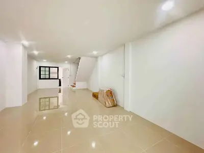 Spacious open-plan living area with glossy tiled floors and modern staircase.