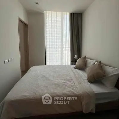 Modern bedroom with large window and stylish decor in a contemporary apartment.