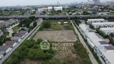 Aerial view of a vacant plot surrounded by residential houses and greenery, ideal for development.