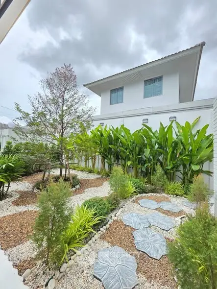 Charming garden view with lush greenery and modern two-story house exterior.