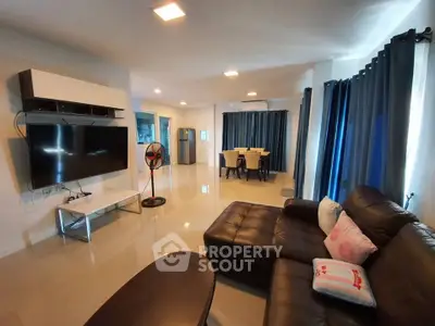 Spacious modern living room with sleek furniture and large TV, perfect for family gatherings.