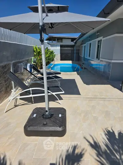 Charming poolside patio with sun loungers and umbrella in modern home exterior