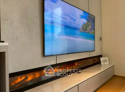 Modern living room with sleek fireplace and wall-mounted TV displaying scenic beach view.