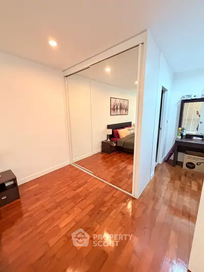 Spacious bedroom with wooden flooring and mirrored closet doors