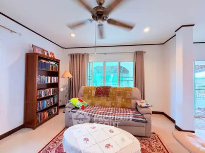 Spacious living room with cozy sofa, ceiling fan, and large windows offering natural light and a view.