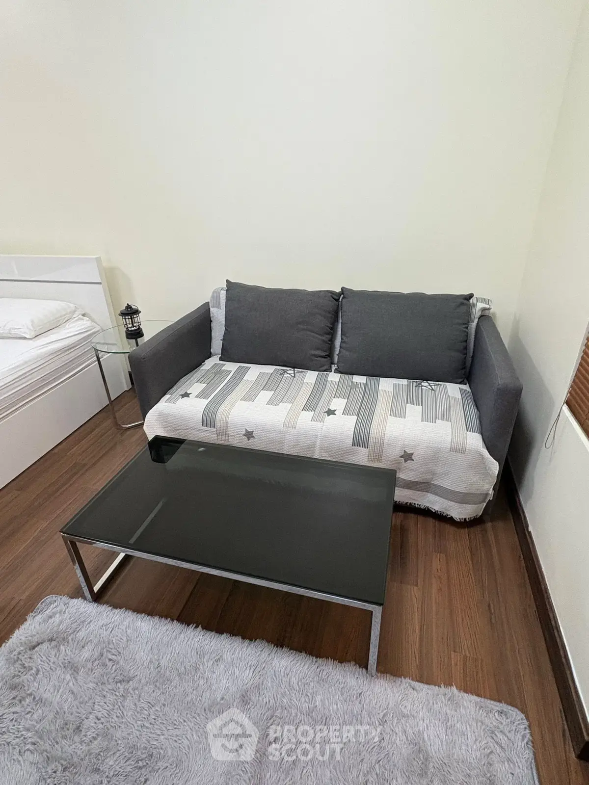 Cozy living room with modern sofa and glass coffee table on wooden floor