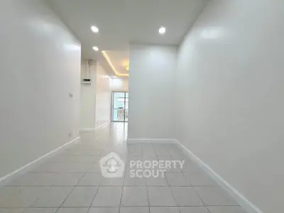 Spacious minimalist interior with tiled flooring and recessed lighting, ideal for modern living.
