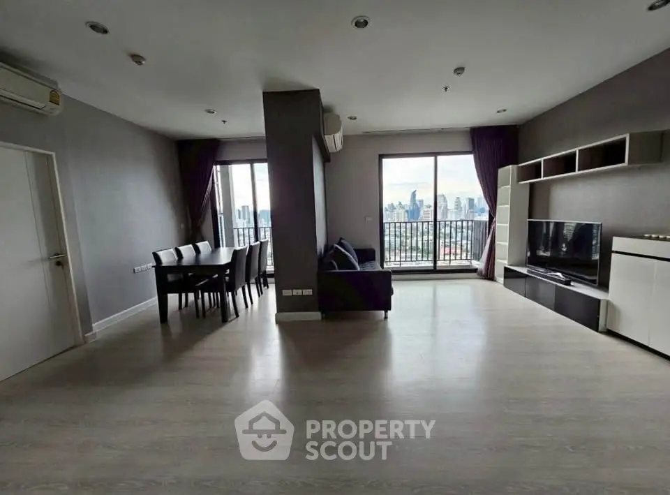 Spacious modern living room with city view and balcony access in high-rise apartment.