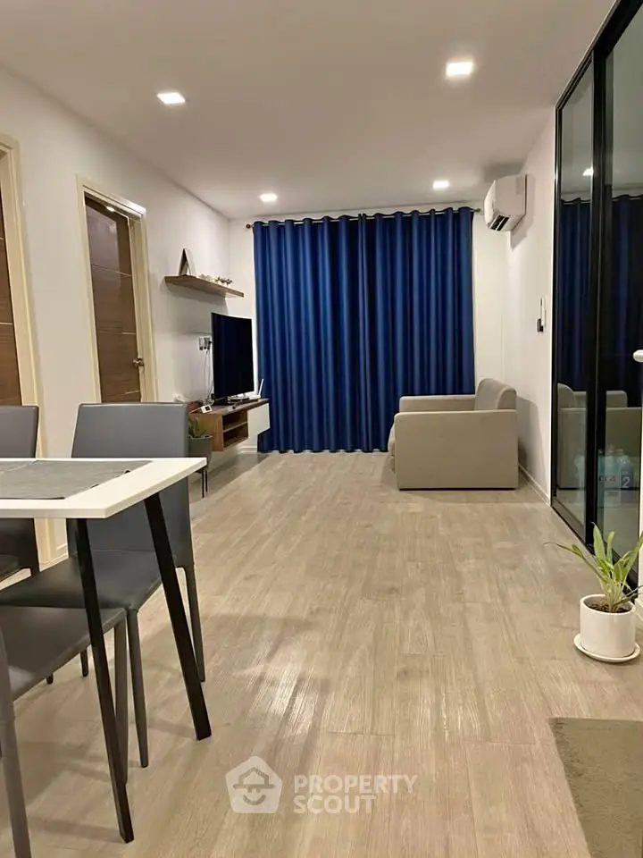 Modern living room with sleek furniture and blue curtains, featuring a spacious layout and stylish decor.