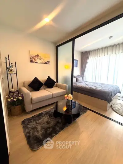 Modern apartment with cozy living room and stylish bedroom separated by glass partition.
