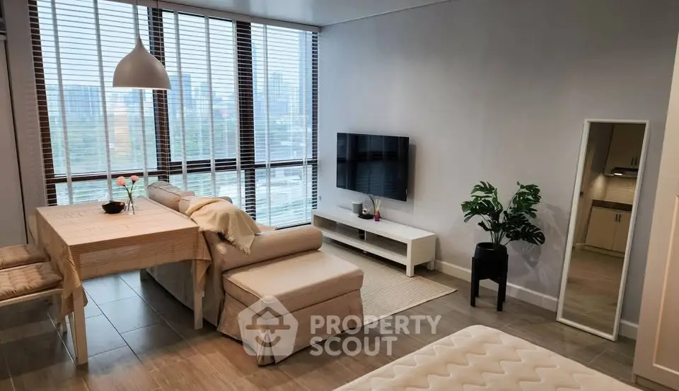 Modern living room with large windows and stylish decor in a high-rise apartment.
