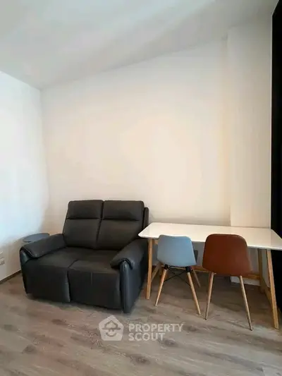 Cozy living room with modern black recliner and stylish dining table with chairs.