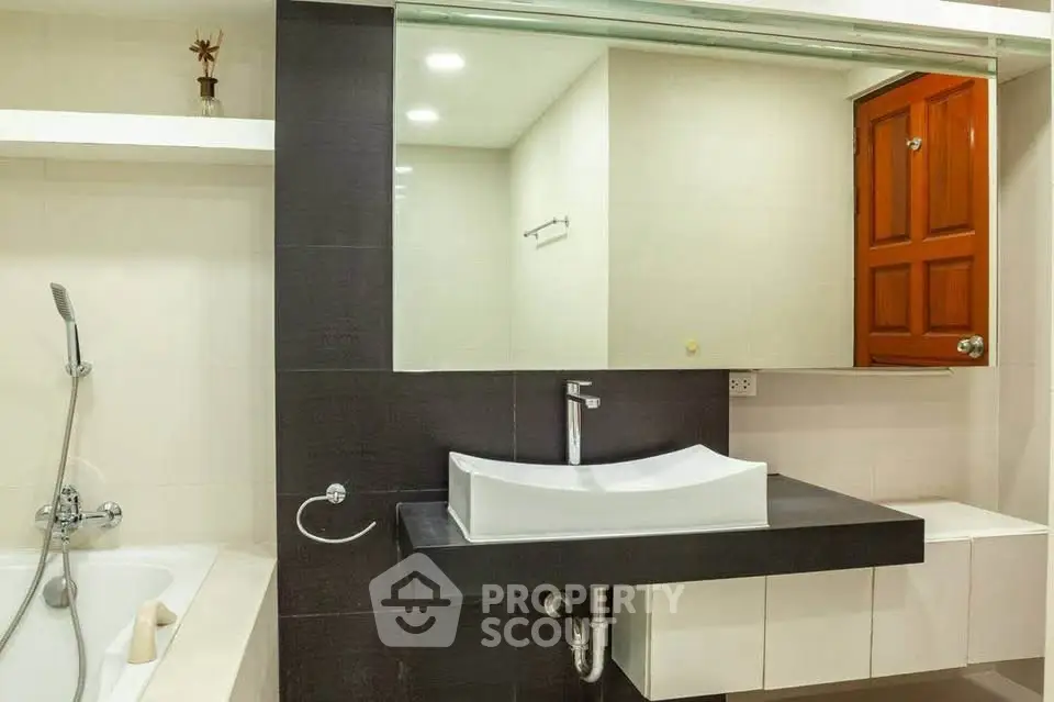 Modern bathroom with sleek sink and bathtub, featuring elegant design and ample lighting.