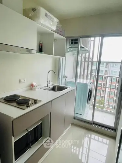 Modern kitchen with sleek appliances and balcony view in urban apartment