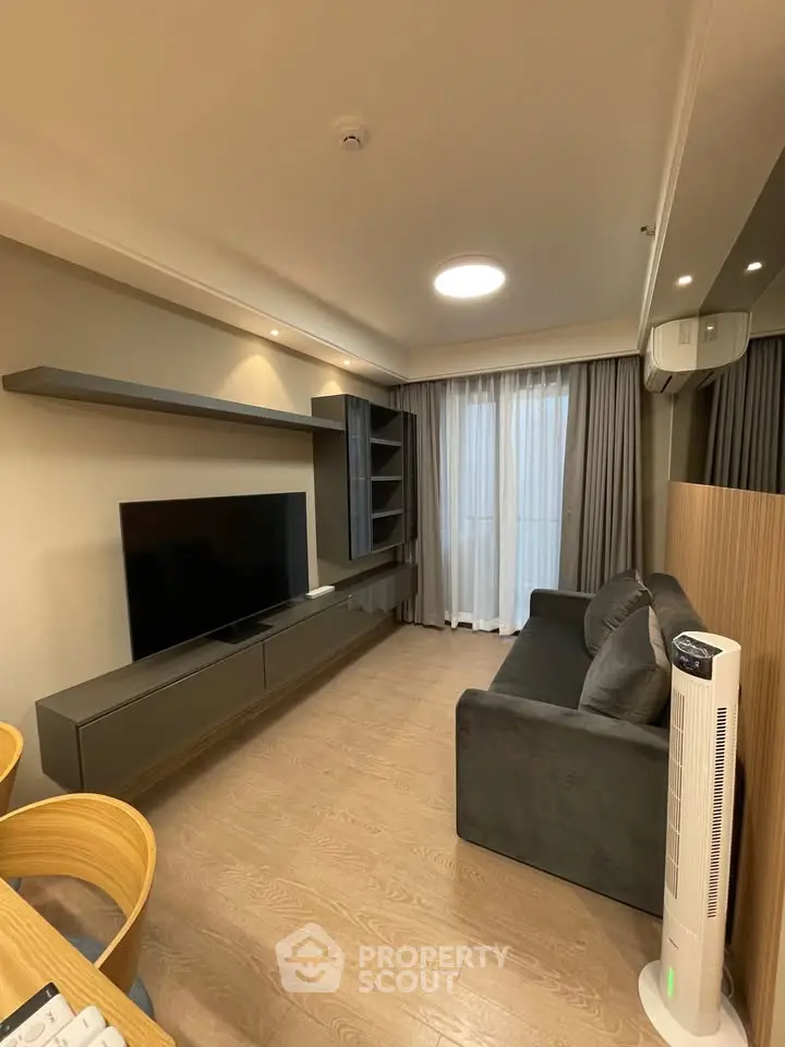 Modern living room with sleek furniture and large TV, featuring a cozy sofa and stylish shelving.