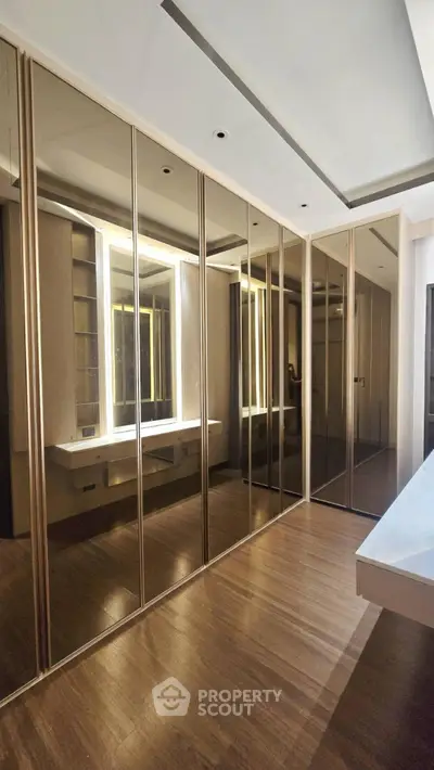 Luxurious walk-in closet with mirrored doors and elegant lighting