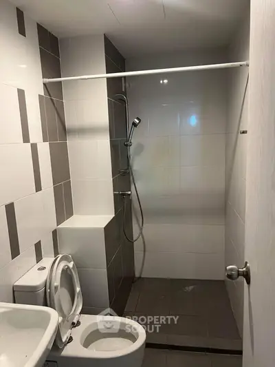 Modern bathroom with sleek shower and tiled walls in contemporary apartment.
