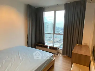 Modern bedroom with large window offering stunning city views, featuring sleek furniture and elegant curtains.