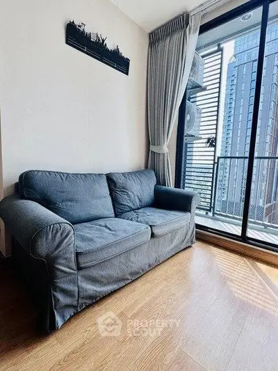 Modern living room with cozy sofa and city view balcony in high-rise apartment.