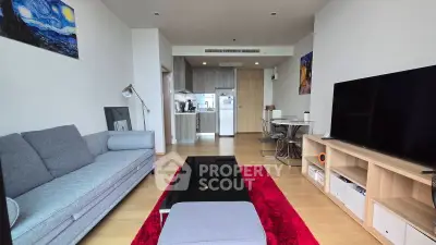 Modern living room with open kitchen, stylish decor, and vibrant red rug