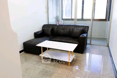 Modern living room with sleek black sofa and stylish coffee table in bright apartment.