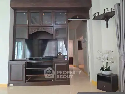 Elegant living room with dark wood entertainment center and large TV, perfect for modern living.