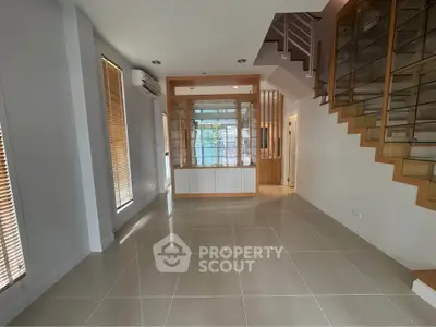 Spacious modern living room with sleek staircase and large windows for natural light.