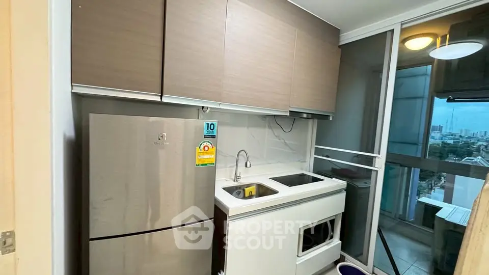 Modern compact kitchen with stainless steel fridge and city view balcony