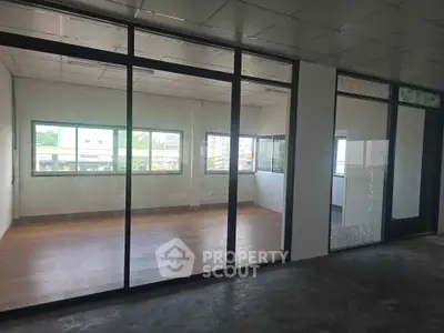 Spacious office space with large windows and glass partitions for modern work environment.