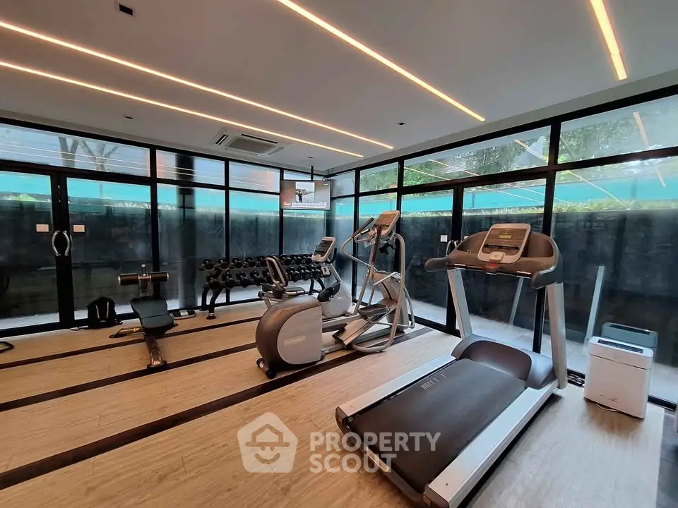 Modern gym with state-of-the-art equipment and large windows in a luxury residential building.
