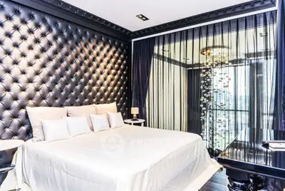 Luxurious bedroom with tufted wall and floor-to-ceiling windows offering stunning views.