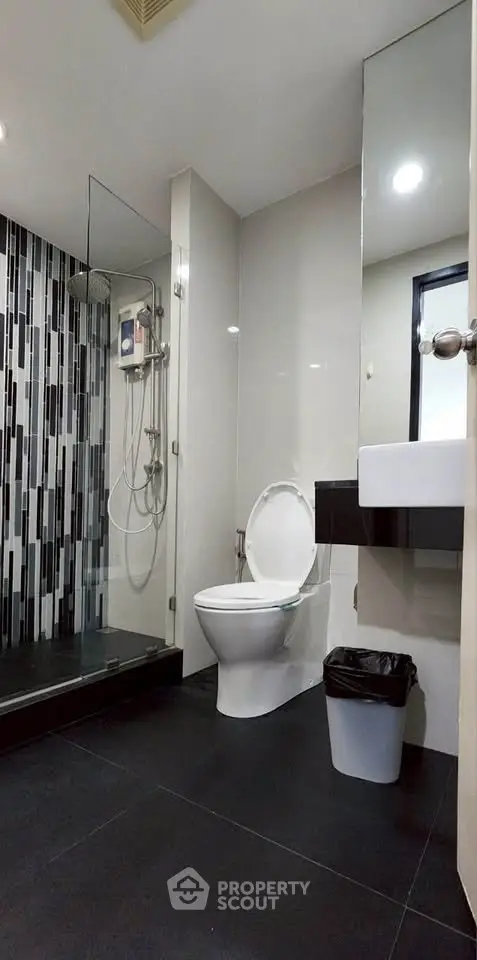 Modern bathroom with sleek design, featuring a glass shower and contemporary fixtures.